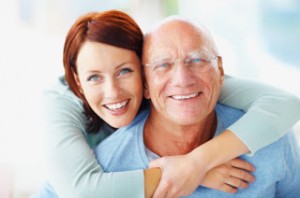 Closeup of an attractive young woman embracing her grandfather from back